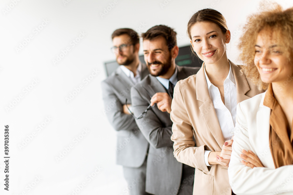 Smiling young business woman standing with group of corporate colleagues in a row together Smiling young business woman standing with group of corporate colleagues in a row together