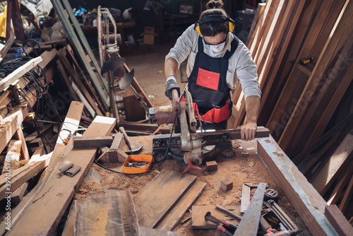 Carpenter man cutting wood with saw. craftsman working workshop factory industry. Capenter worker with mask protection.