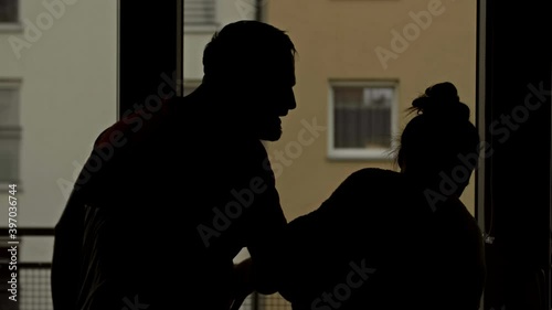 Silhouettes of a quarreling couple in the dark against the background of a night window.
