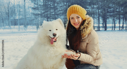 Portrait of happy smiling young woman owner with her white Samoyed dog in winter park © rohappy