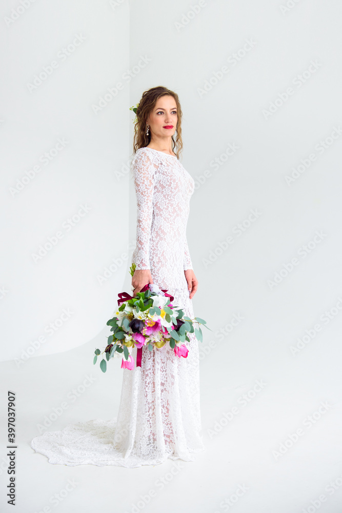 joyful girl bride in a white knitted dress posing with a bouquet of flowers joyful girl bride in a white knitted dress posing with a bouquet of flowers