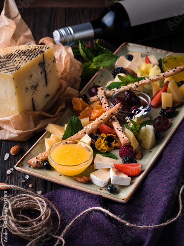 Cheese plate served with grapes and nuts. Assorted cheeses camembert, brie, parmesan blue cheese, goat with grapes, gressini sticks, cashews, honey and jam. photo