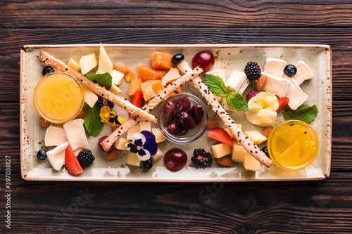 Cheese plate served with grapes and nuts. Assorted cheeses camembert, brie, parmesan blue cheese, goat with grapes, gressini sticks, cashews, honey and jam. photo