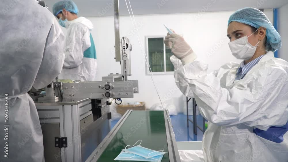 Group of two inspector worker wearing ppe suite, face protective mask and glove discussion and checking quality mask of production line of manufacturing at lab in industry factory Group of two inspector worker wearing ppe suite, face protective mask and glove discussion and checking quality mask of production line of manufacturing at lab in industry factory