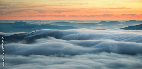 Wavy blankets of thick fog over valleys and hills