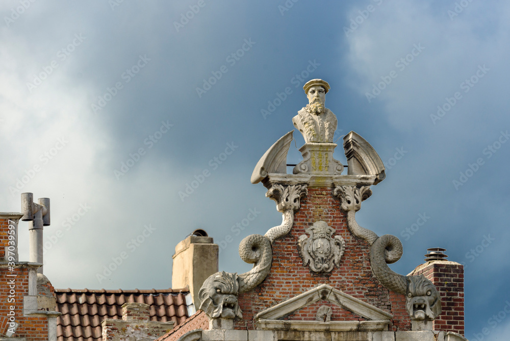 old pediment with statue on a house of the Graslei in the historic city center of Ghent
