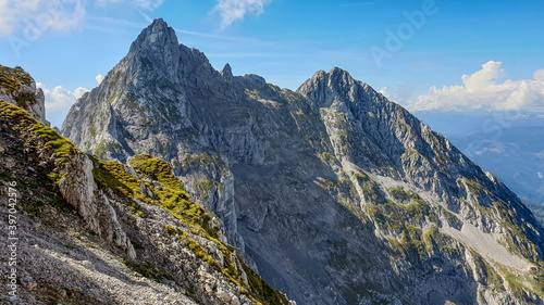 A panoramic view on Alpine slopes in Austria. There are sharp ans steep mountains and high peaks around. The Alpine slopes are almost barren, just moss overgrowing the slopes. Serenity and freedom.