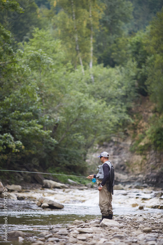 Mature man using rod for catching fish in mountain river