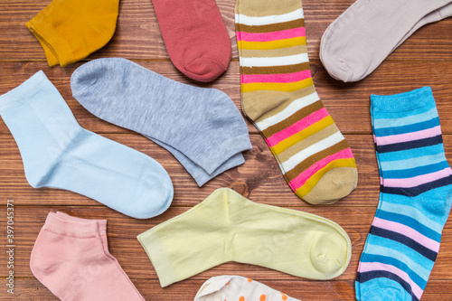 multicolored new socks in different sizes stacked on a wooden background. clothes for women