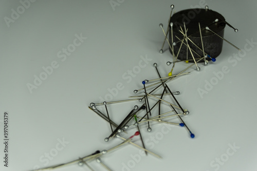needles and magnet on a white background