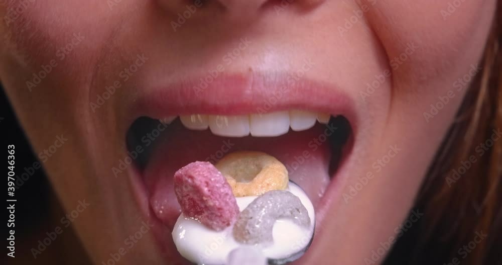 Young woman mouth eating yogurt with colorful hoops cereal