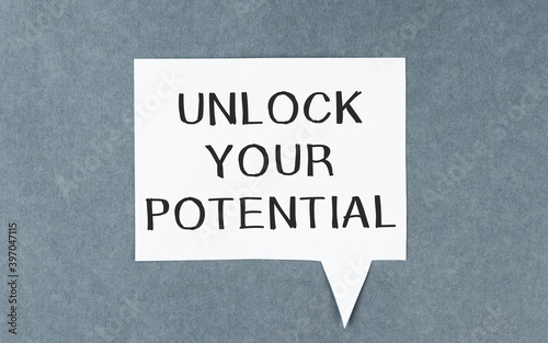 Unlock your potential. Motivational or inspirational quote handwritten on paper on a wooden table.