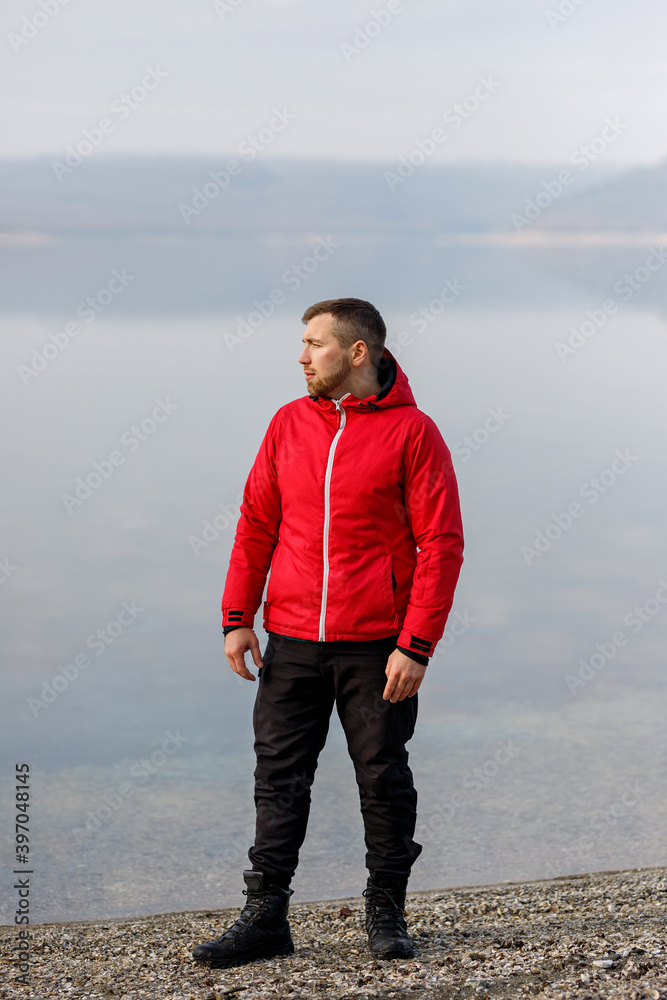 A young man in a sports suit stands by the river