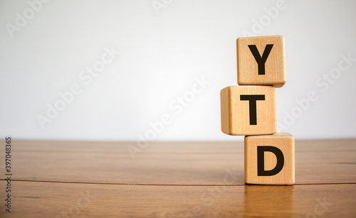 YTD symbol. Word 'YTD - year-to-date' on cubes on a beautiful wooden table, white background. Business and YTD concept.