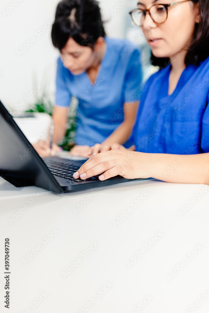 Female doctor and nurse using the laptop in the clinic