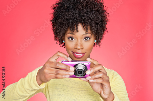 Portrait of an African American woman holding a camera over colored background © moodboard