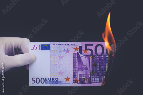 A five hundred euro bill is burning on a black background.
