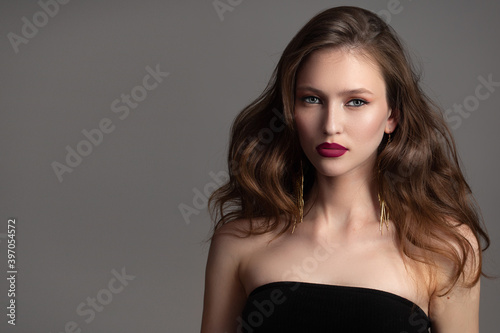 portrait of a beautiful woman with wavy hair and gold earrings. Perfect makeup, red lipstick. Copycpase