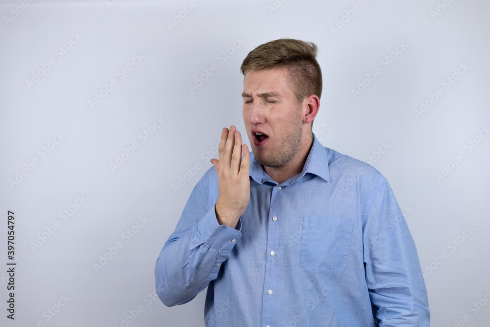 Business young man wearing a casual shirt over white background bored yawning tired covering mouth with hand. Restless and sleepiness. Business young man wearing a casual shirt over white background bored yawning tired covering mouth with hand. Restless and sleepiness.