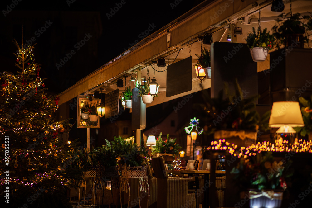 A cozy street cafe with Christmas decorations on the street of the old town in Prague. Christmas illumination. Bokeh garlands in the background. Christmas, winter, new year concept. A cozy street cafe with Christmas decorations on the street of the old town in Prague. Christmas illumination. Bokeh garlands in the background. Christmas, winter, new year concept.