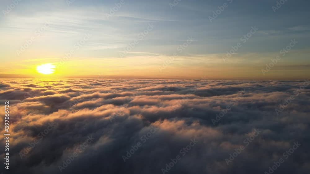 Aerial view of vibrant yellow sunrise over white dense clouds with blue sky overhead. Aerial view of vibrant yellow sunrise over white dense clouds with blue sky overhead.