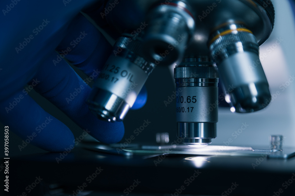 Fototapeta premium Close-up shot of sample slide and microscope with metal lens at laboratory.