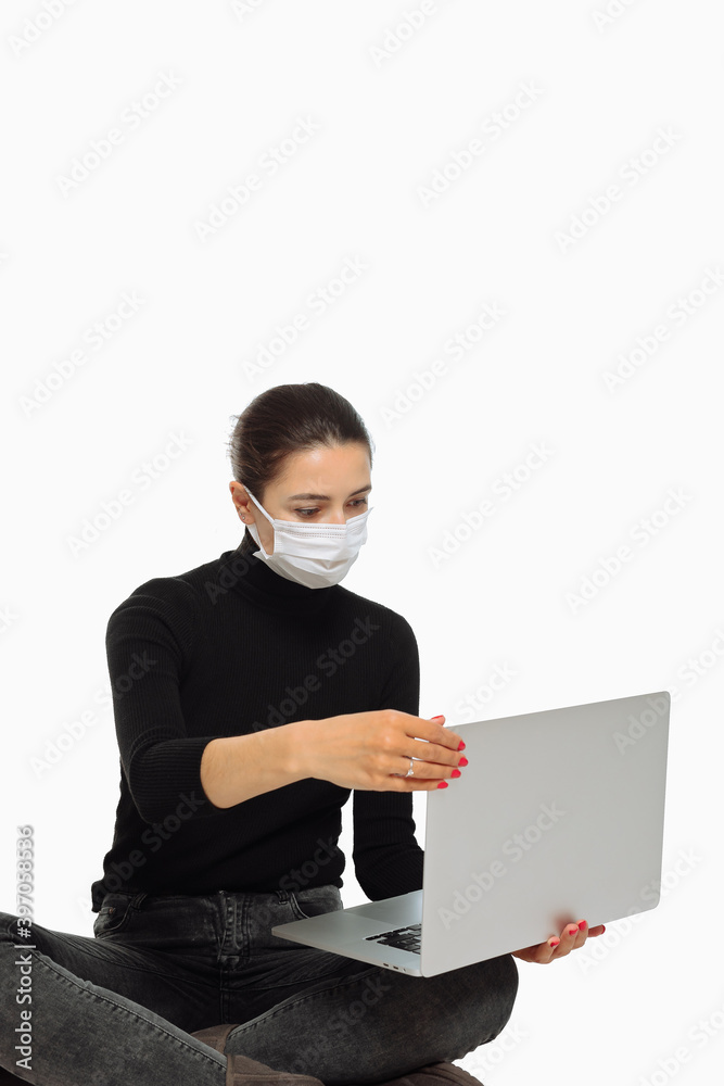 Beautiful young woman in black turtleneck with face mask indoors. Concept photo with copy space. Businesswoman sitting and open laptop. Copyspace for text or design on white background. Beautiful young woman in black turtleneck with face mask indoors. Concept photo with copy space. Businesswoman sitting and open laptop. Copyspace for text or design on white background.