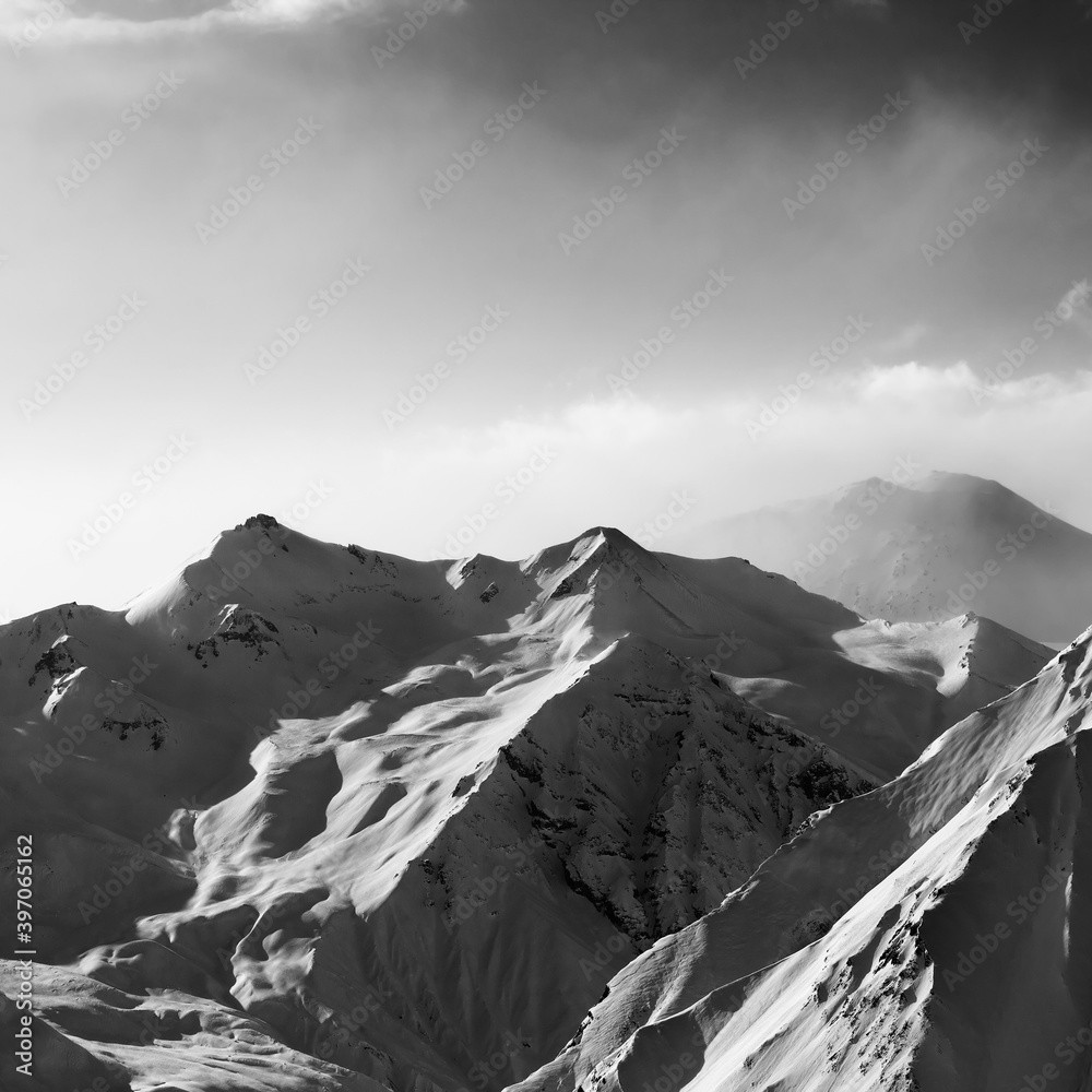 Obraz premium Black and white view on snowy sunlight mountains in early fog morning