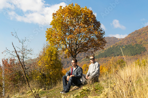 Young men taking a break after long walking in autumn nature