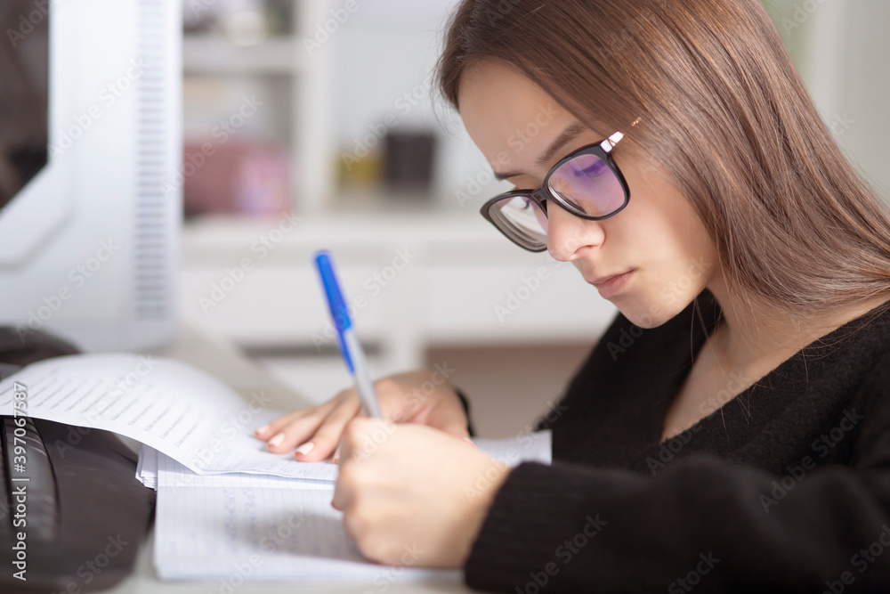 Preparation for exams. Young teenage girl at home studies, writes, reads, remembers Preparation for exams. Young teenage girl at home studies, writes, reads, remembers