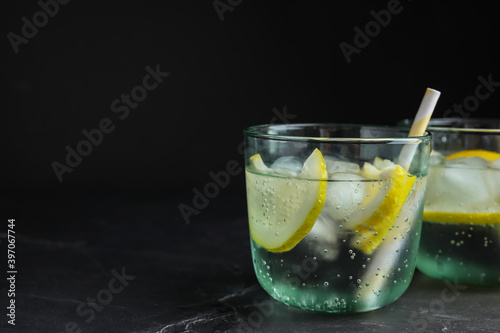 Soda water with lemon slices and ice cubes on grey table. Space for text