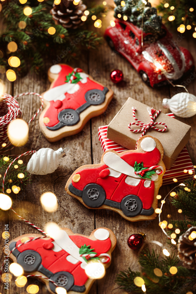 Christmas gingerbread cars, fir branches, red decorations, lights garland, gift boxes on wooden background. Merry Christmas and New Year holiday. Xmas cookies, close up, bokeh