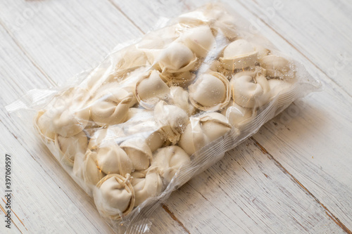 frozen dumplings in packaging on a white wooden background.