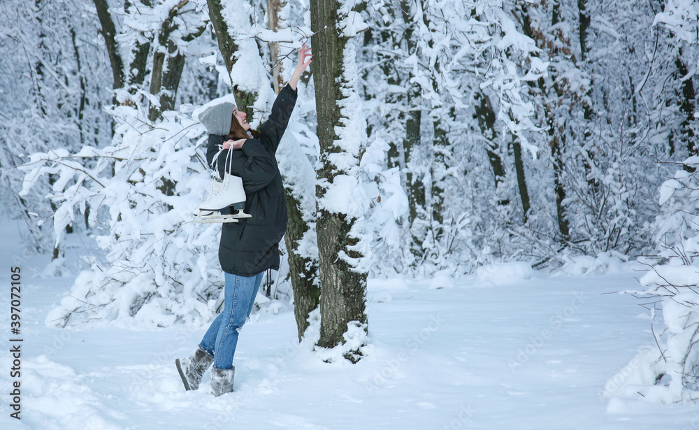 Young woman walks in the winter forest. Girl with skates behind her back. Russian Winter. Too much snow