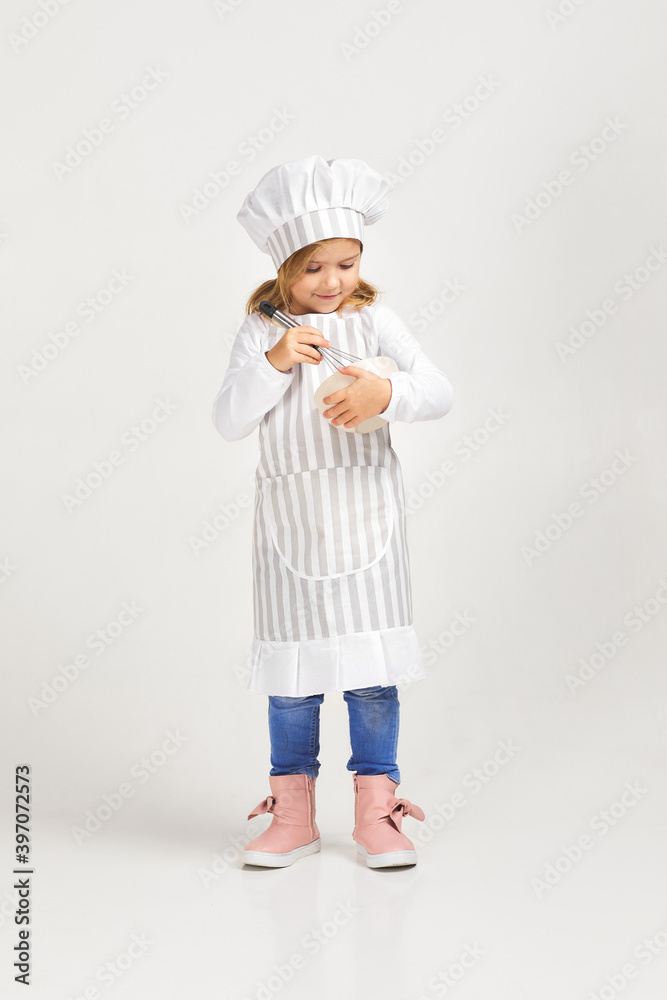 adorable little girl in cooker uniform with bowl and whisk. child dreams of becoming a chef adorable little girl in cooker uniform with bowl and whisk. child dreams of becoming a chef