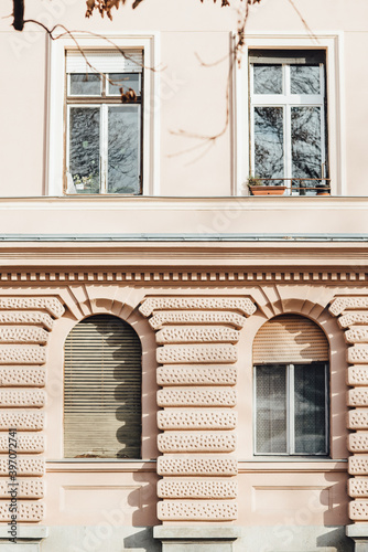 Facade with four windows with blind of pink or apricot color residential building in Budapest during sunny day