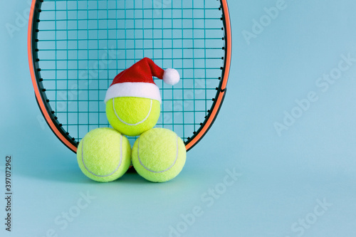 three smiley yellow tennis balls in santa hat with racket , xmas decoration, tennis sport concept