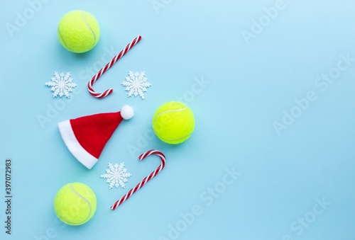 Santa hat , tennis balls , candy canes and snow flakes on blue background. Merry Christmas and New year concept with tennis balls. sport lifestyle. Flat lay, flatlay, copy space.