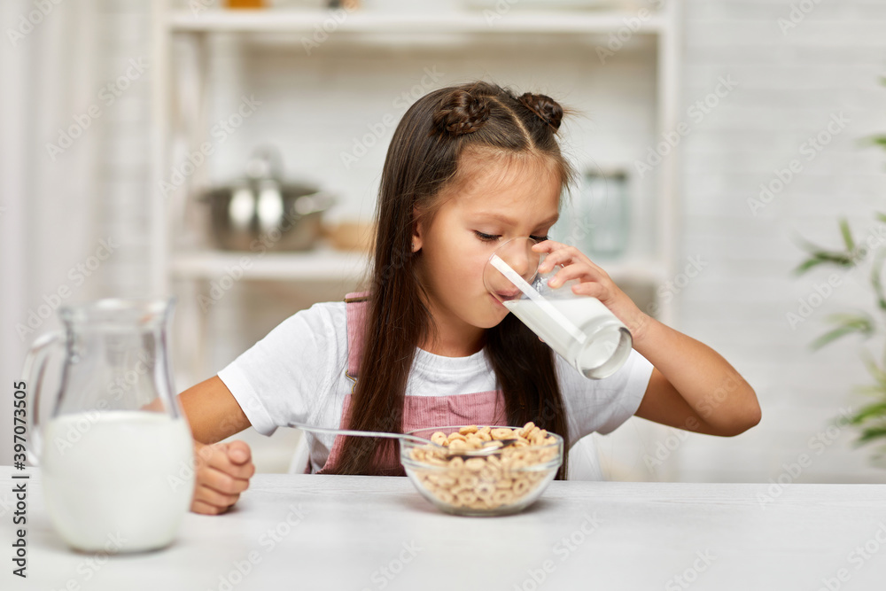 cute little girl eating breakfast: cereal with the milk. child drinking milk in the kitchen. healthy breakfast cute little girl eating breakfast: cereal with the milk. child drinking milk in the kitchen. healthy breakfast