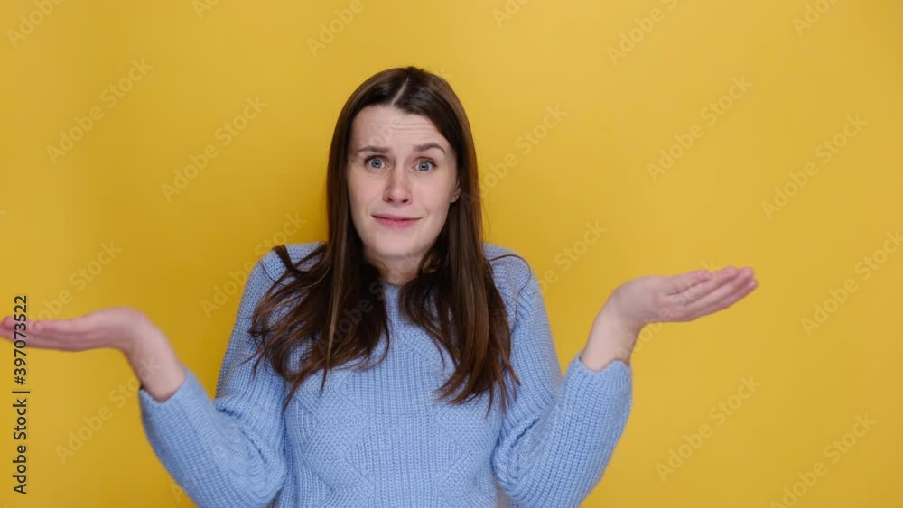 Side profile view of worried irritated disgusted young woman turn around camera spreading hands sweating, dressed in blue sweater, isolated on yellow studio wall. Emotion people lifestyle concept Side profile view of worried irritated disgusted young woman turn around camera spreading hands sweating, dressed in blue sweater, isolated on yellow studio wall. Emotion people lifestyle concept