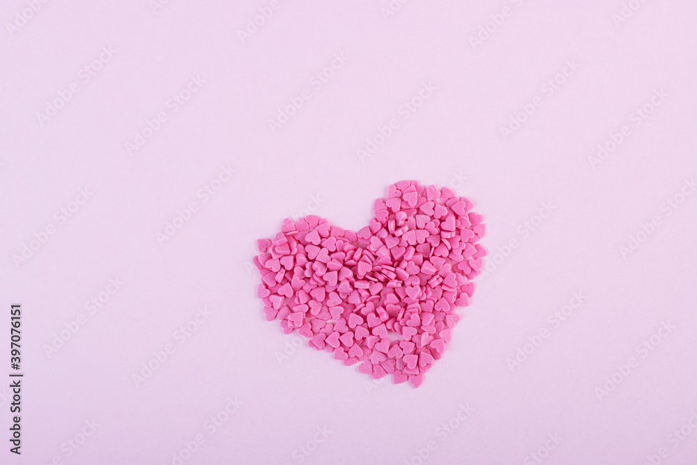 Hundreds of tiny pink heart-shaped hearts lie in the shape of a large heart as a symbol of romantic love Hundreds of tiny pink heart-shaped hearts lie in the shape of a large heart as a symbol of romantic love