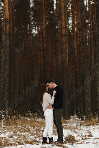 Young man and woman kissing in the winter forest. With the place for your text. Love, relationship, winter holidays. Winter couple photo ideas