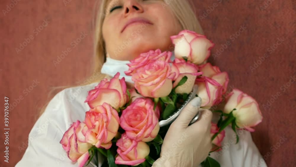 Doctor day theme. Blonde doctor in uniform enjoying a bouquet of fresh flowers. Thank you doctors for the work. Holiday of a medical worker. Selective focus, shallow depth of field Doctor day theme. Blonde doctor in uniform enjoying a bouquet of fresh flowers. Thank you doctors for the work. Holiday of a medical worker. Selective focus, shallow depth of field