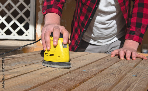 Man with checkered shirt sanding a pallet