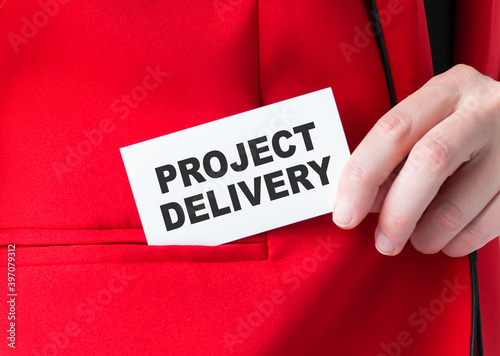 Businessman puts a card with text PROJECT DELIVERY in his pocket, business concept