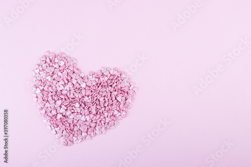 Hundreds of tiny pink heart-shaped hearts lie in the shape of a large heart as a symbol of romantic love