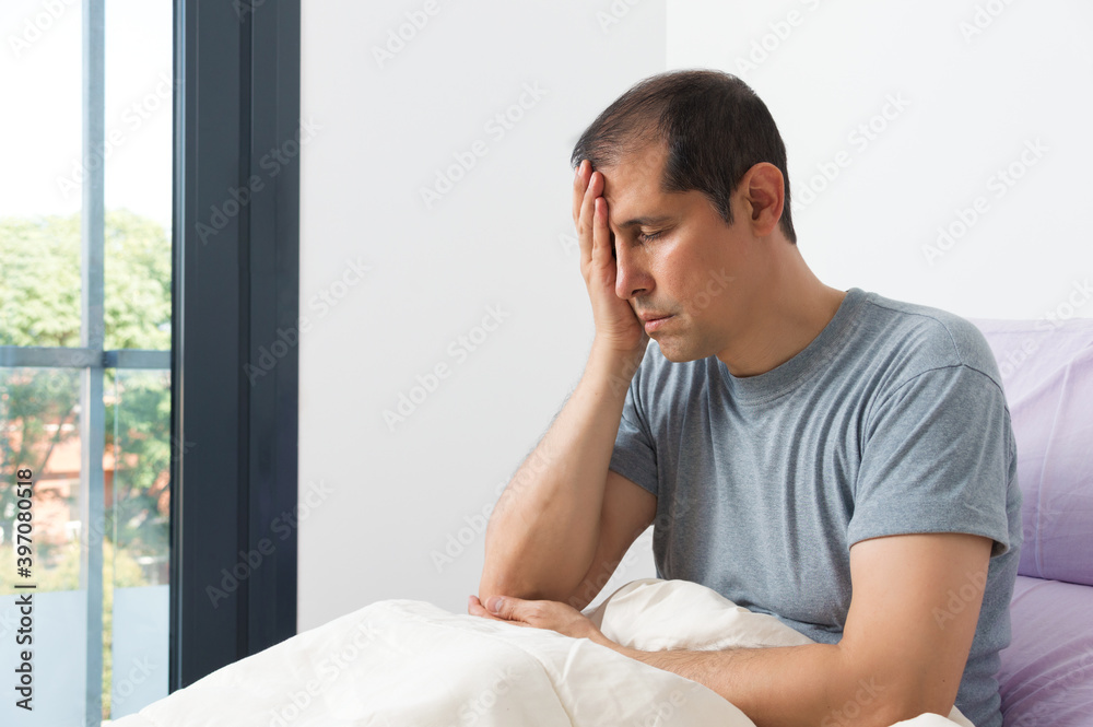 Shot of a young man suffering migraine complaining in his bedroom Shot of a young man suffering migraine complaining in his bedroom