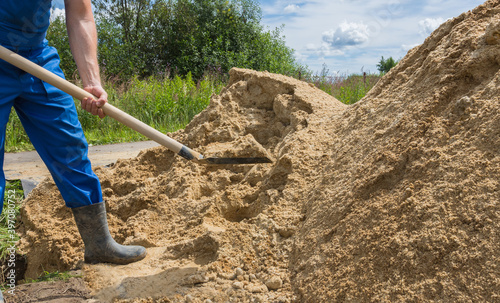 a worker shovels river sand into a large pile