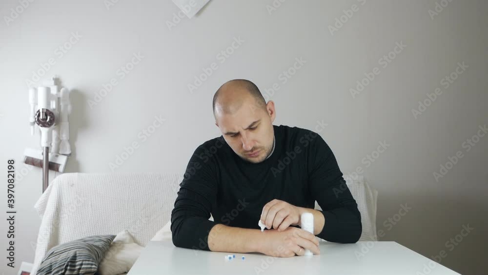 A bald man at home treats a wart on his arm treated with salicylic acid
