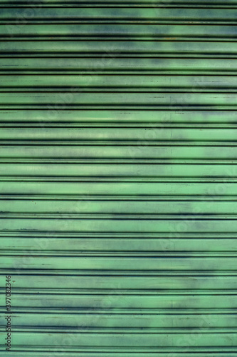 Zielono turkusowe miejskie tło, metalowa roleta sklepowa.